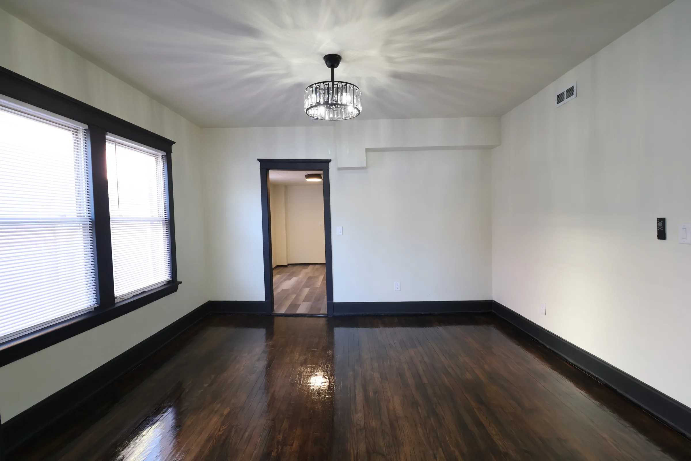 Finished living room with dark trim, restored floors, and updated lighting
